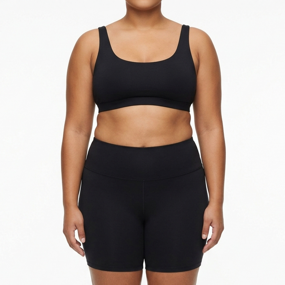 Person wearing a black sports bra and shorts on a white background